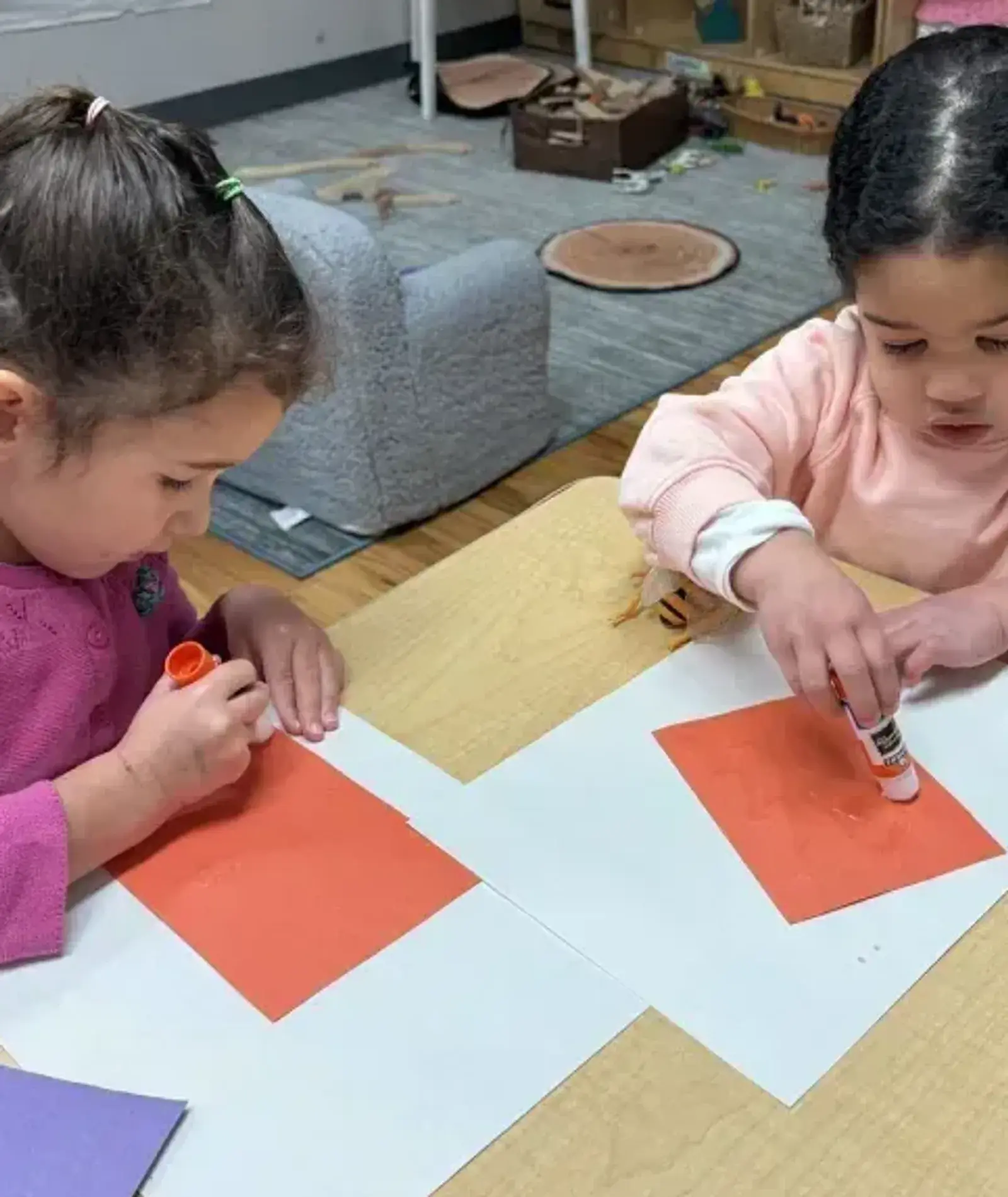 Two preschoolers gluing orange paper squares at a table at Songbird Academy in Chicago